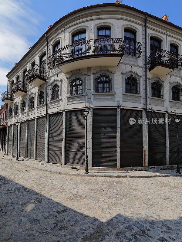 白灰色、新古典主义风格的屋角，位于老巴扎区鹅卵石铺就的ruruica Alush Koprencka和ruruica petranq Nasi街角。korca -阿尔巴尼亚- 257